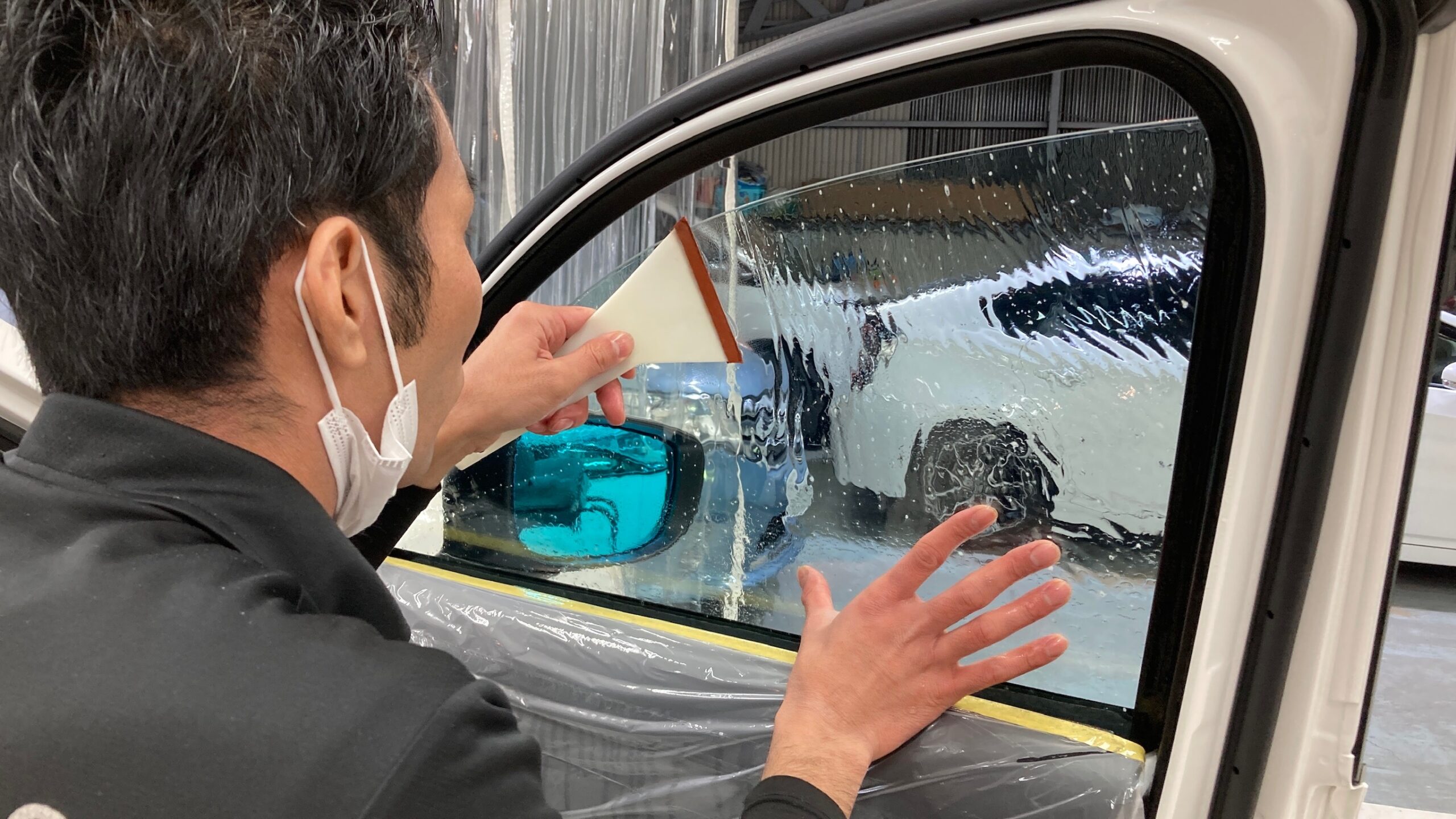 CX-5のカーフィルム施工手順：フィルムをヘラで伸ばしている様子