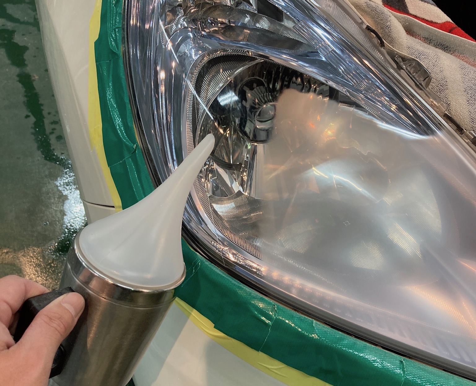 ホンダ・フィットのヘッドライトリファイン施工工程：蒸着作業をしている様子