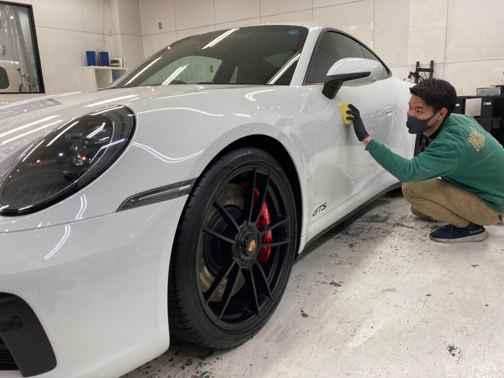 ポルシェ・911 GTS・ハイモースコートザグロウの仕上げ作業：ドアにコーティング剤を塗布している様子