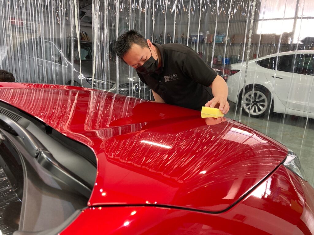 トヨタ・RAV4の仕上げ作業：コーティング剤をボディに塗布している様子