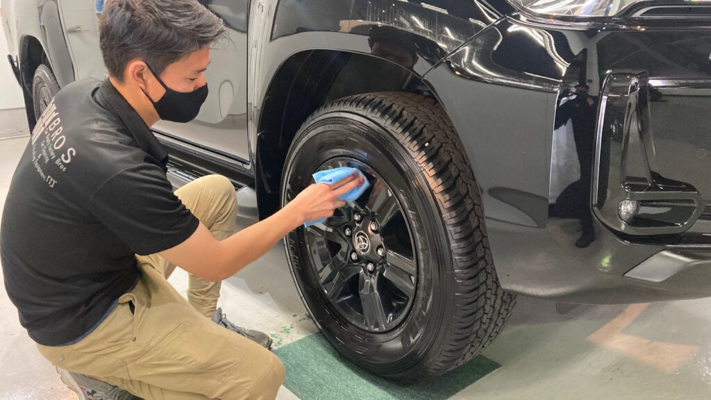 トヨタ・ハイラックスのクラスM施工：仕上げ作業工程：ホイールを綺麗に拭きあげている様子