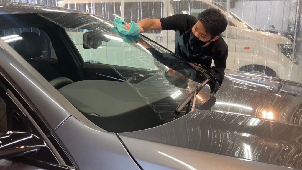 BMW・１シリーズ：クラスM施工：仕上げ作業工程：最終チェックをし、フロントガラスを拭いている様子