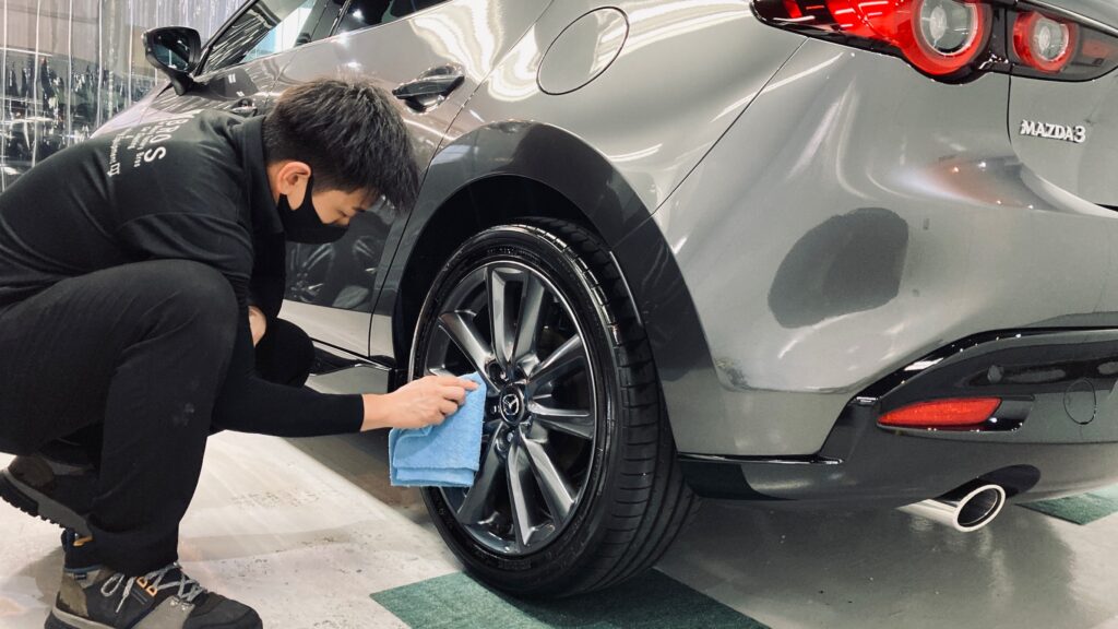 マツダ・MAZDA3：クラスM施工：仕上げ作業工程：ホイールを拭きあげている様子