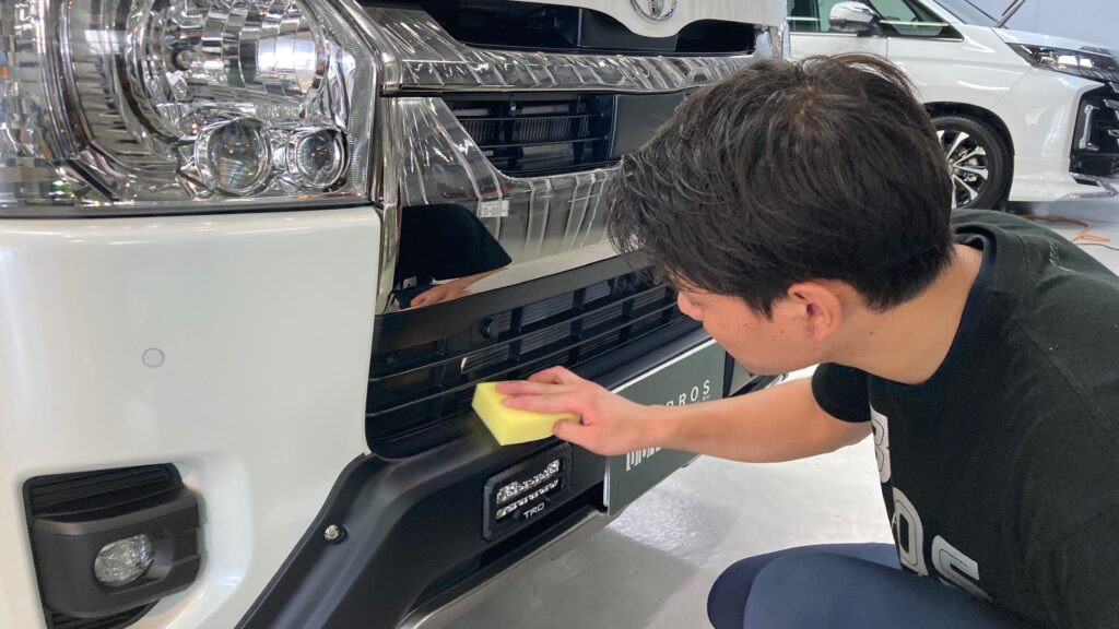 トヨタ・ハイエース・クラスM施工：仕上げ作業工程：樹脂パーツに専用のコーティング剤を塗布しレベリングしている様子