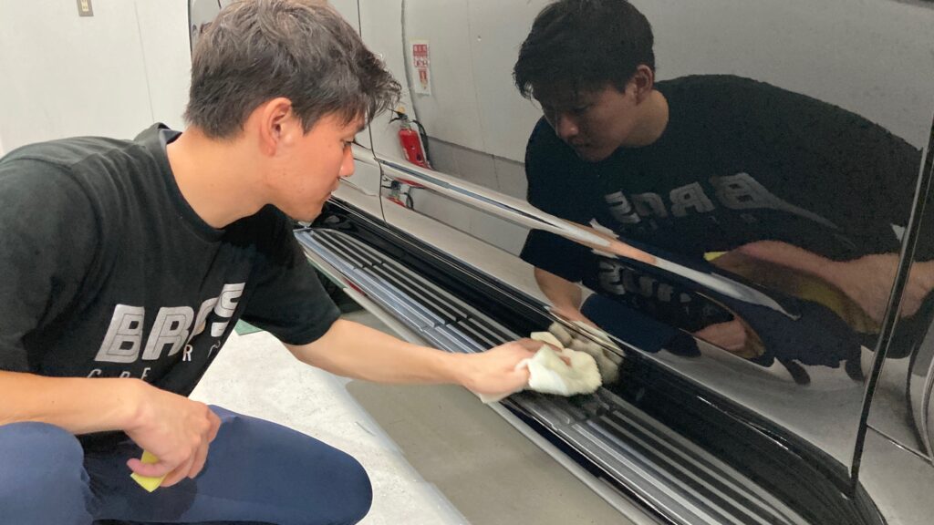 トヨタ・ランドクルーザー：クラスM施工：仕上げ作業工程：樹脂パーツにコーティング剤を塗布し拭き上げている様子２